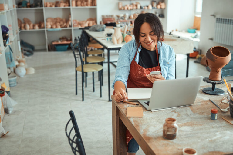 artist smiling in front of laptop in workshop