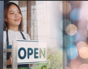 woman holding sign inside window "Open"