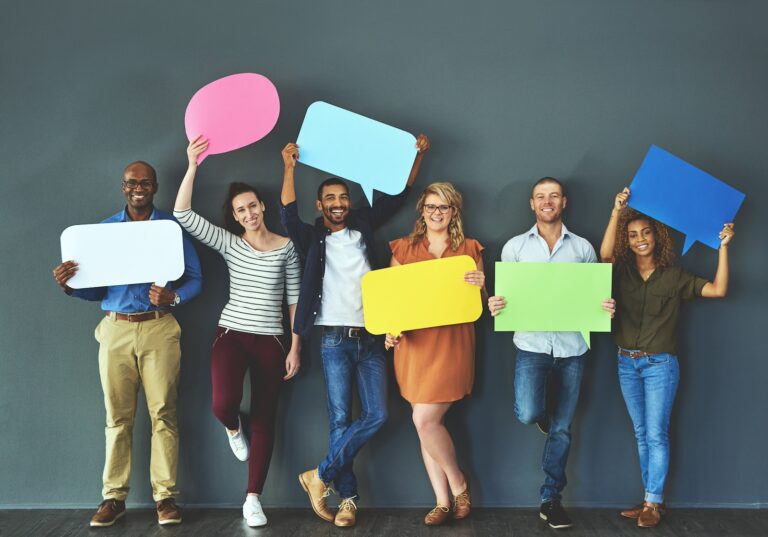 Diverse group of people holding up speech bubbles against a gray background