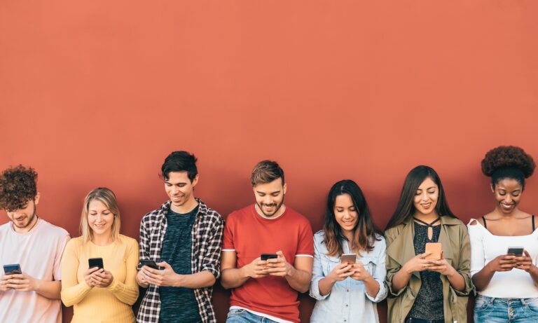 Group of young people standing against a red background using mobile apps