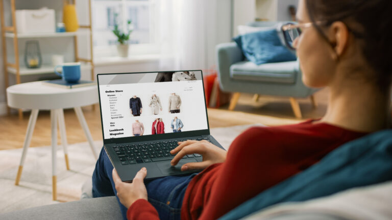 Woman sitting down using her laptop for online shopping.