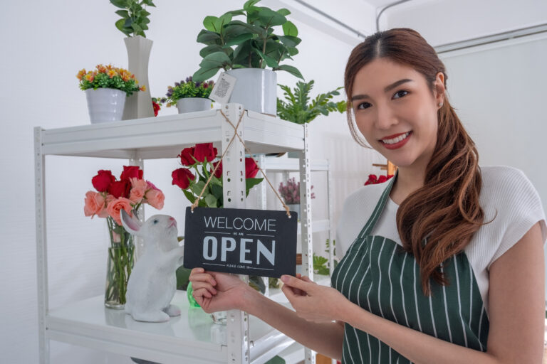 woman holding open sign in her store
